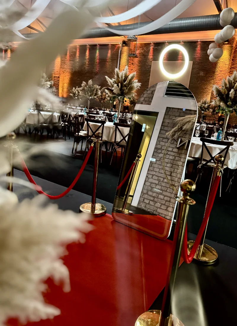 Fotospiegel neben gedeckten Tischen und Pampasdekoration in einer Eventlocation
